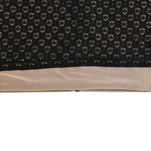 Dettaglio in pizzo nero con motivi geometrici su fodera beige della gonna corta