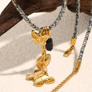 Dettaglio della collana a farfalla in oro 18K con corda su supporto in legno