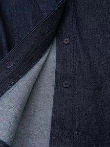 Détail du tissu en jean bleu foncé avec armure sergée et bouton mat à quatre trous