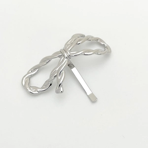 Detailed view of silver bow hair clip featuring a woven texture and metallic finish