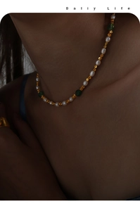 Close-up of vintage necklace with freshwater pearls, green gems and gold beads