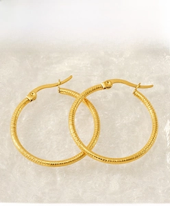 Close-up of gold-plated hoop earrings featuring a sophisticated spiral texture finish