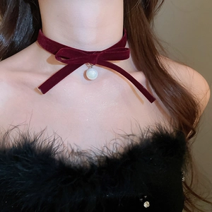 Close-up of burgundy velvet bow choker necklace with elegant white pearl pendant detail