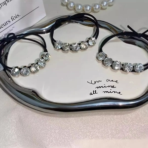 Close-up of black elastic hair ties with shimmering crystals on a silver tray