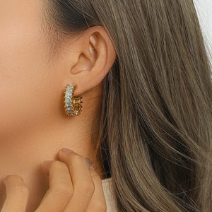 Détail macro de boucles d'oreilles en C en acier doré avec zircons rectangulaires