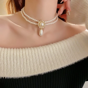 Detail of double-layer pearl necklace with golden flower and water drop pendant