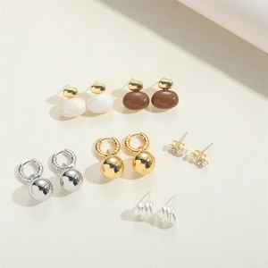 Detail showing various 14K gold plated and silver earrings with pearls on beige background