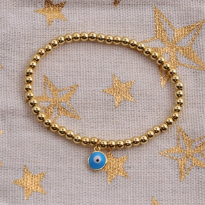 Close-up of gold-plated beaded bracelet with blue evil eye enamel charm on star fabric
