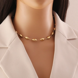 Close-up of a gold beaded chain necklace layered over a beige blazer for a trendy look