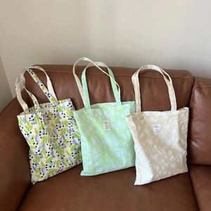 Three textured cotton tote bags with floral and bubble patterns on a brown leather sofa