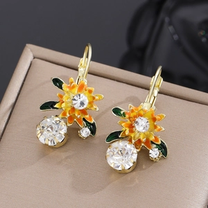 Vue détaillée de boucles d'oreilles tournesol dorées avec émail et cristaux brillants
