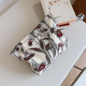 Detail of floral embroidery on off-white fabric pouch with simple wish label