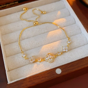 Macro shot of gold plated bracelet with zirconia flower charms in a luxury wooden box
