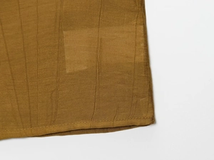 Macro detail of ginger crinkled fabric texture and fine stitching of the midi skirt