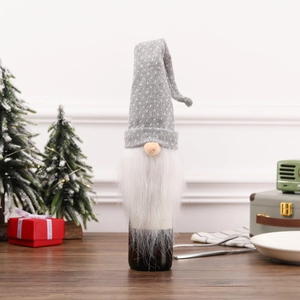 Close-up of grey knitted gnome wine bottle cover with white beard on festive wooden table
