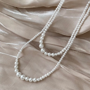Close-up of elegant layered pearl necklace with gradient beads on champagne silk fabric