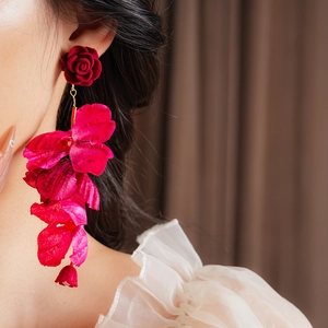 Détail d'une boucle d'oreille fleur en velours rouge avec perle portée par un mannequin