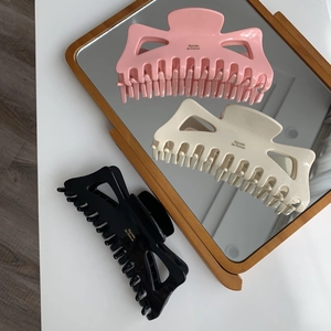Détail de trois grandes pinces à cheveux en acétate en rose, crème et noir classique