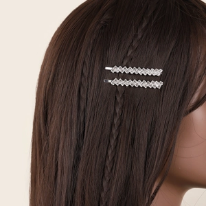 Macro detail of two silver rhinestone hair clips worn on long dark hair for bridal style