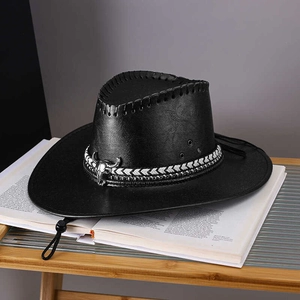 Detail of black faux leather cowboy hat with silver bull skull ornament on a book