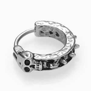 Macro d'une boucle d'oreille punk en argent avec relief de crâne et textures à pointes