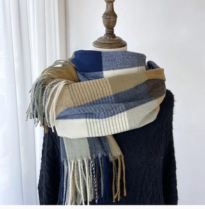 Close-up of thick plaid scarf in blue and tan with soft tassel edges on a mannequin