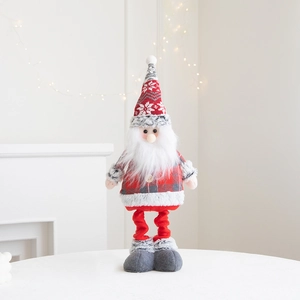Detail of Santa Claus plush doll with long red legs and knitted clothes by white fireplace
