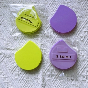 Flat lay of colorful foundation sponges in yellow and purple with SISSIMU brand ribbon