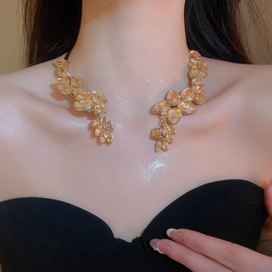 Close-up of champagne gold leaf-shaped crystal necklace on skin with sparkling glitter
