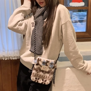 Close-up of plush faux shearling crossbody bag with cow pattern and brand label detail