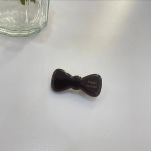 Macro shot of a glossy dark brown jelly bow hair clip with gold France Handmade lettering