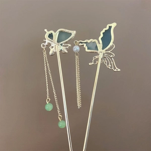 Détail d'une épingle à cheveux papillon dorée avec perles vertes et pompon de style