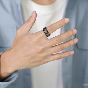 Close-up of black stainless steel spinner ring for men with engraved Lord's Prayer details