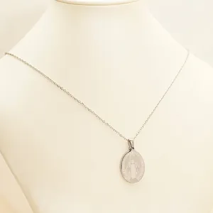 Vintage stainless steel cross necklace with oval Virgin Mary relief pendant on white stand