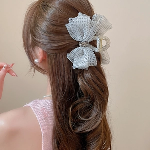 Detail of grey polka dot tulle bow hair claw clip with crystal center on hair