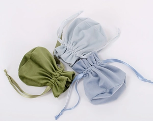 Detailed view of olive green, light grey, and light blue velvet drawstring gift bags