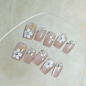 Handmade nude pink cat-eye press-on nails with white flowers and sparkling rhinestones