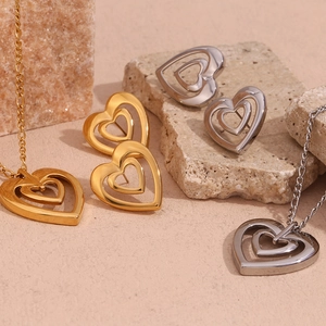 Macro view of hollow heart necklace and earrings in gold and silver steel finishes
