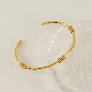 Detail of 18K gold-plated C-shaped cuff with twisted rope texture and metallic luster