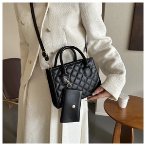 Detail of black quilted shoulder bag featuring a matching mini coin purse hanging charm