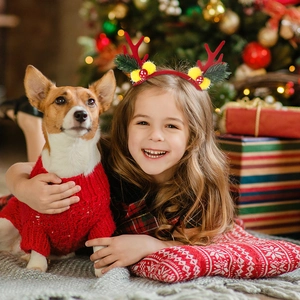 Girl wearing festive Christmas reindeer antler headband with festive tree background