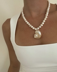 Close-up van een parelketting van zoetwaterparels met een schelphanger op een model