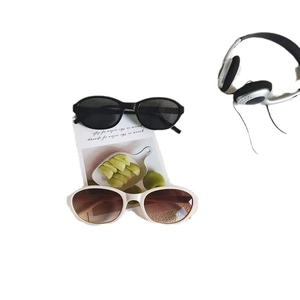 Retro small oval sunglasses in black and beige displayed on a green artistic card