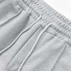 Detalle de pantalones cortos grises de punto gofrado con cintura elástica y cordón