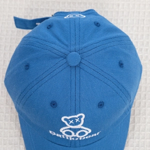 Detailed embroidery of a cartoon bear with XX eyes on a blue toddler baseball cap