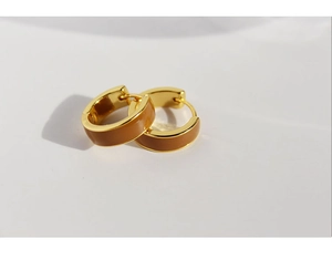 Detailed macro view of golden C-shaped hoop earrings with brown enamel finish