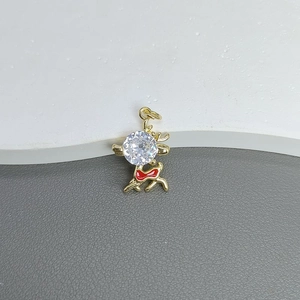 Macro detail of a golden elk pendant with a large clear zircon and red bow accent