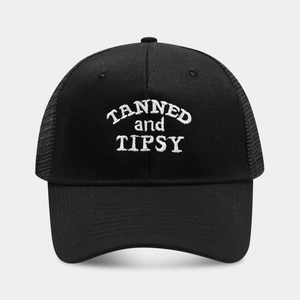 Close-up of black mesh trucker hat featuring white TANNED and TIPSY embroidery detail