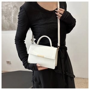Detail of white square handbag with gold metal clasp and smooth glossy finish