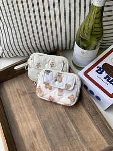 Quilted floral and bear print mini pouches displayed on a tray with wine and gift box